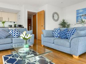 a living room with two blue couches and a glass table at Apartment 22, Horizon View in Westward Ho +11 photos