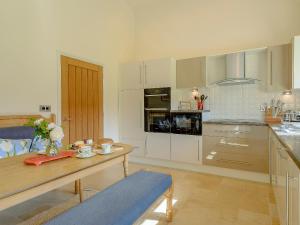 a kitchen with white cabinets and a wooden table at Courtyard Lodge in Edwinstowe