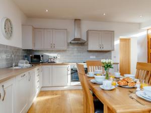 a kitchen with white cabinets and a wooden table at The Old Laundry - Uk12136 in Hewelsfield +16 photos
