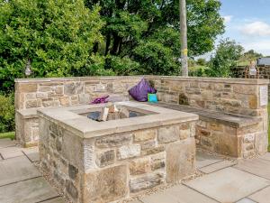 a stone fire pit in a stone wall at Alton Hall Cottage in Ashover