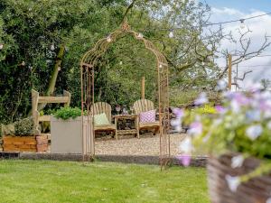 a gazebo with two chairs and a table in a garden at Alton Hall Cottage in Ashover
