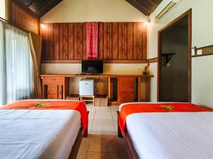 a room with two beds and a television in it at The Lavana Green Asri Cottage in Senggigi +45 photos