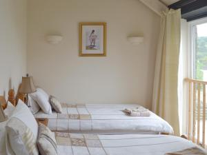two beds in a bedroom with a window at Meadow Mews in Chillington