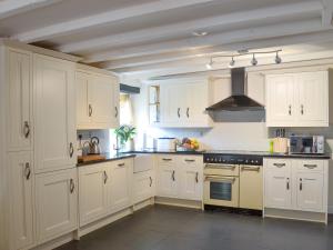 a kitchen with white cabinets and a stove top oven at Meadow Mews in Chillington