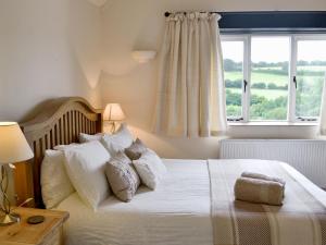 a bedroom with a bed with white pillows and a window at Meadow Mews in Chillington