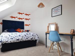 a bedroom with a bed and a desk and a blue chair at No 1 Fox Burrow-Uk44306 in Lenwade +12 photos