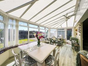 a conservatory with a table with flowers on it at Broadoak Barn in Ellesmere