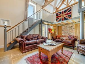 a living room with leather furniture and a staircase at The Gin Gang in Whorlton
