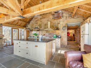 a kitchen with white cabinets and a stone wall at The Gin Gang in Whorlton