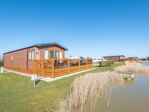 a wooden cabin next to a body of water at Reed Roost - Uk37726 in Skegness