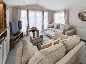 a living room with a couch and a tv at Reed Roost - Uk37726 in Skegness