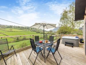 a patio with a table and chairs and an umbrella at Wern Ddu Cottage in Pen-y-bont-fawr