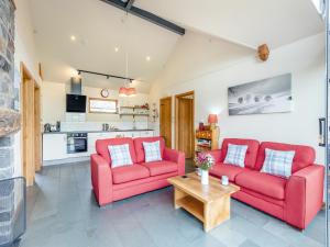 a living room with two red couches and a table at Wern Ddu Cottage in Pen-y-bont-fawr