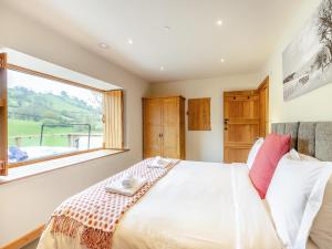 a bedroom with a large bed with a window at Wern Ddu Cottage in Pen-y-bont-fawr