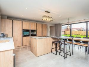 a kitchen with wooden cabinets and a table with stools at The Pines - Ukc4615 in Dunholme