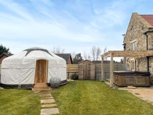 a yurt in a yard next to a house at Ember Sky Yurt - Uk51679 in Beadnell +2 photos