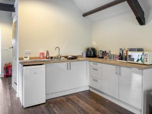 a kitchen with white cabinets and a sink at Ember Sky Yurt - Uk51679 in Beadnell