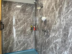 a bathroom with a shower with a gray marble wall at Ember Sky Yurt - Uk51679 in Beadnell