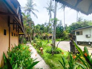 a garden with palm trees and a house at The Lavana Green Asri Cottage in Senggigi