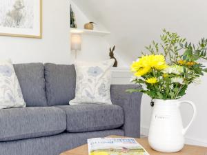 a living room with a couch and a vase with flowers at The Apple Loft in Mickleton
