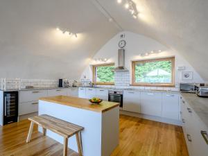 a kitchen with white cabinets and a wooden table at Jack Strawbale House - Uk7521 in Strontian +20 photos