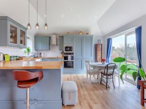 a kitchen with blue cabinets and a table with chairs at The Lodge At Edenbridge in Shepton Mallet