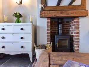 a fireplace in a living room with a white dresser at Peppercorn Cottage in Cheriton