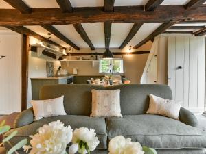 a living room with a couch and a kitchen at Peppercorn Cottage in Cheriton