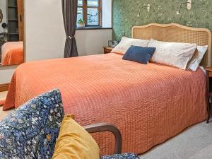 a bedroom with a large bed with an orange bedspread at Yr Efail - Hw7387 in Llanymawddwy
