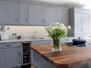 a kitchen with a vase of flowers on a wooden counter at Seacliff in Corton +11 photos
