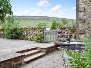a patio with a stone wall and stairs and a table at Prospect Cottage in Kettlewell