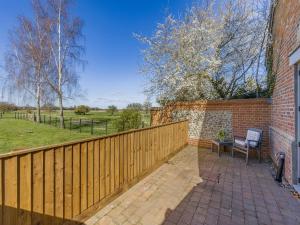 a fence with a table and a chair on a patio at Orchard Barn in Thurlton