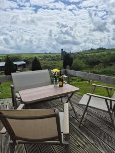 a table and chairs on a deck with a view at The Paddock at Pioneer Billys in Camborne