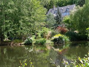 a house and a pond in front of a house at Gite Le Clos de Sée in Chérencé-le-Roussel