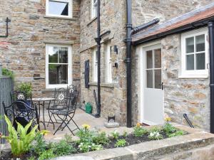 a stone house with a patio and a table and chairs at Arkle Terrace in Reeth