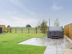 a barbecue grill sitting in a yard next to a fence at The Dairy - Uk34564 in Whitchurch