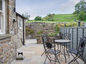 a patio with a table and chairs and a stone wall at Arkle Terrace in Reeth