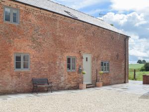 a brick building with a bench in front of it at The Dairy - Uk34564 in Whitchurch