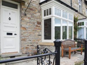 a wooden bench in front of a brick building with a white door at Arkle Terrace in Reeth