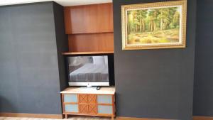 a living room with a tv and a painting on the wall at 雲林斗六御花園汽車旅館 in Douliu +8 photos