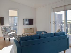 a living room with a blue couch and a tv at Cree Lodge - Uk13636 in Creetown