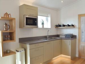 a kitchen with a sink and a microwave at Cree Lodge - Uk13636 in Creetown +9 photos