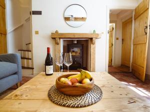 a bowl of fruit on a table with a bottle of wine at New Lane Cottage in Worstead