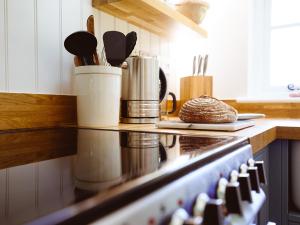 a kitchen counter with a stove with utensils at New Lane Cottage in Worstead