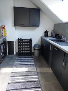 a kitchen with black cabinets and a sink and a rug at Appartement meublé Tilff in Esneux
