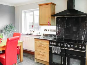 a kitchen with a black stove and a red chair at Ty'n Rallt in Bodorgan