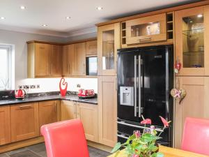 a kitchen with wooden cabinets and a black refrigerator at Ty'n Rallt in Bodorgan