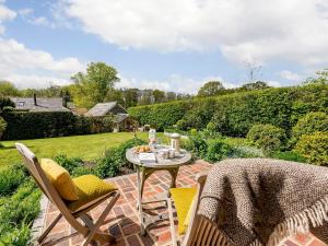 a patio with a table and chairs in a garden at Brook Farm Annex in Tenterden