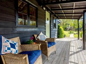 a porch with two wicker chairs and awning at Brook Farm Annex in Tenterden