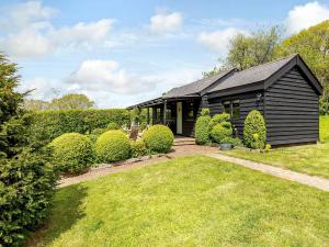 a small black house with a yard in front of it at Brook Farm Annex in Tenterden